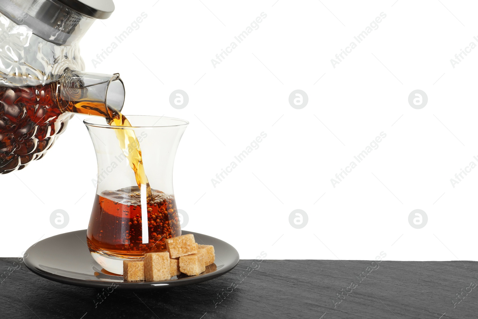 Pouring hot Turkish tea into glass cup at table against white background, closeup Photo of Pouring hot Turkish tea into glass cup at table against white background, closeup
