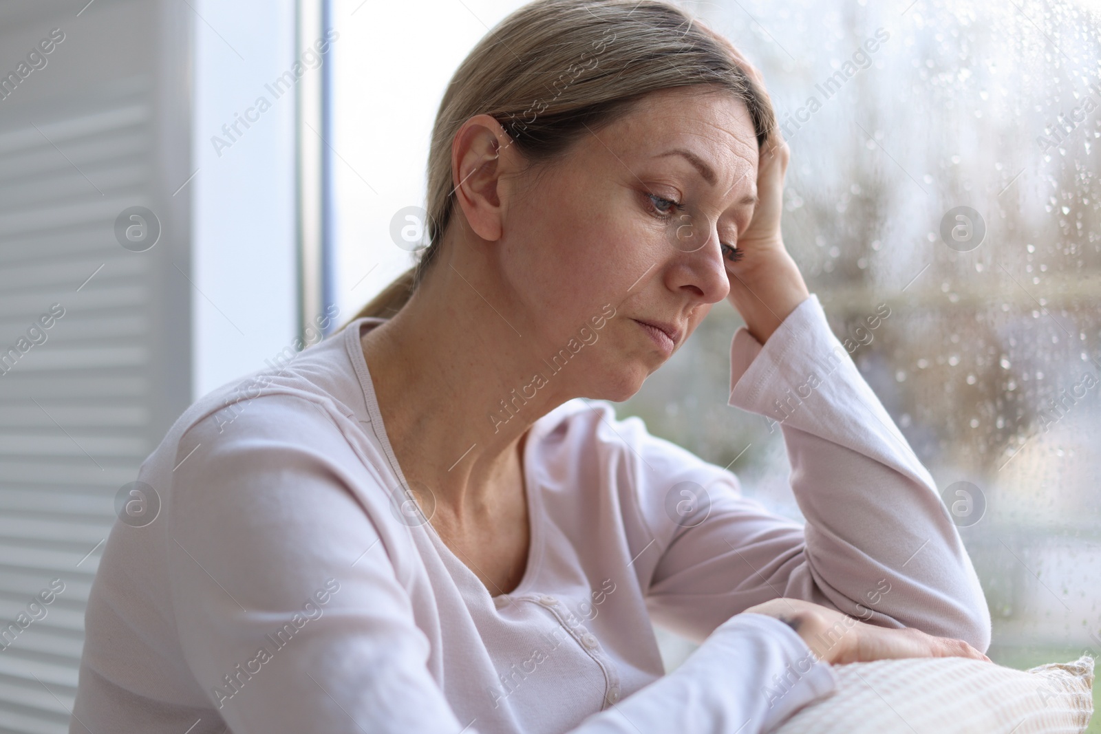 Depressed woman near window at home on rainy day Photo of Depressed woman near window at home on rainy day