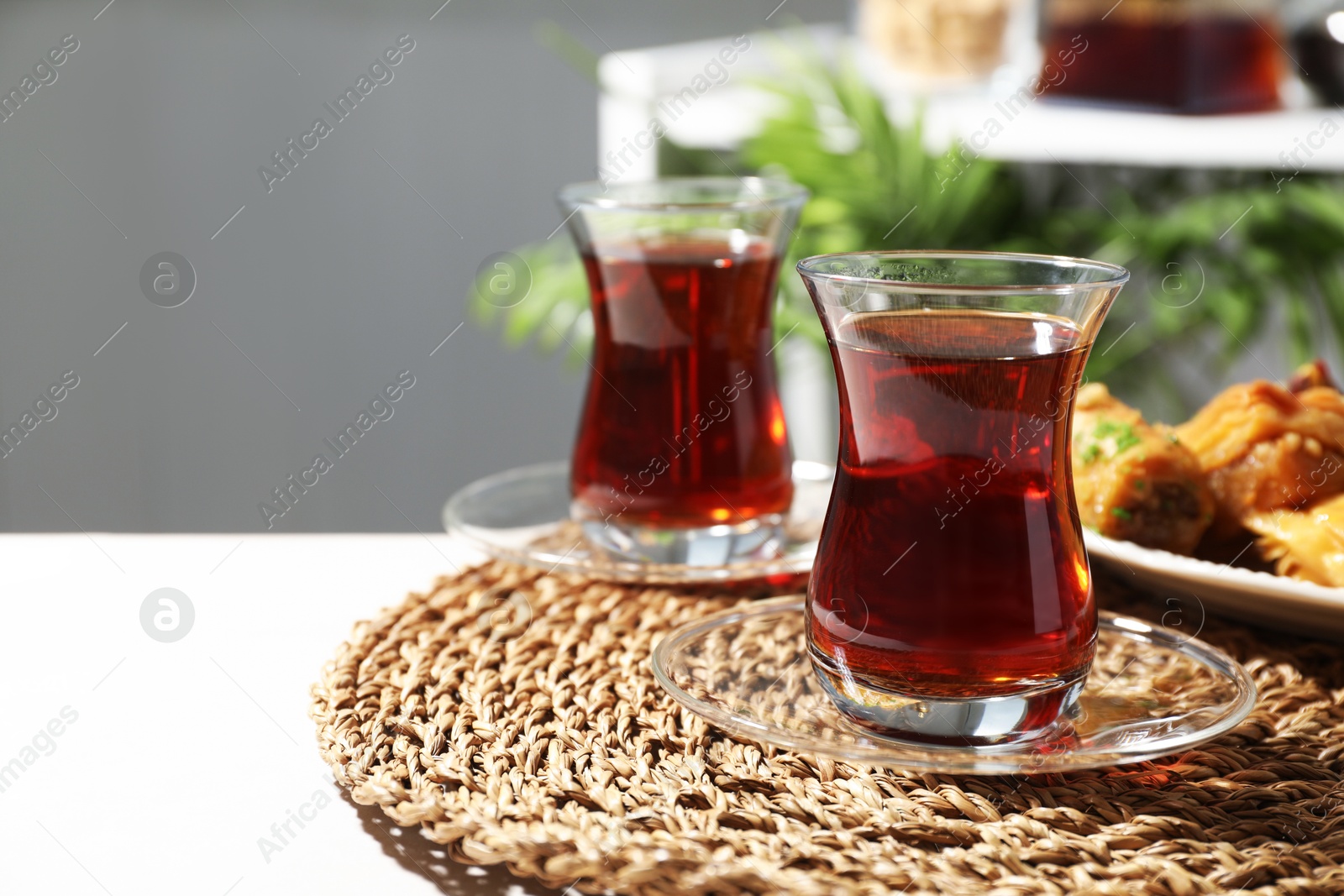 Traditional Turkish tea in glass cups and fresh baklava on white table, closeup. Space for text Photo of Traditional Turkish tea in glass cups and fresh baklava on white table, closeup. Space for text