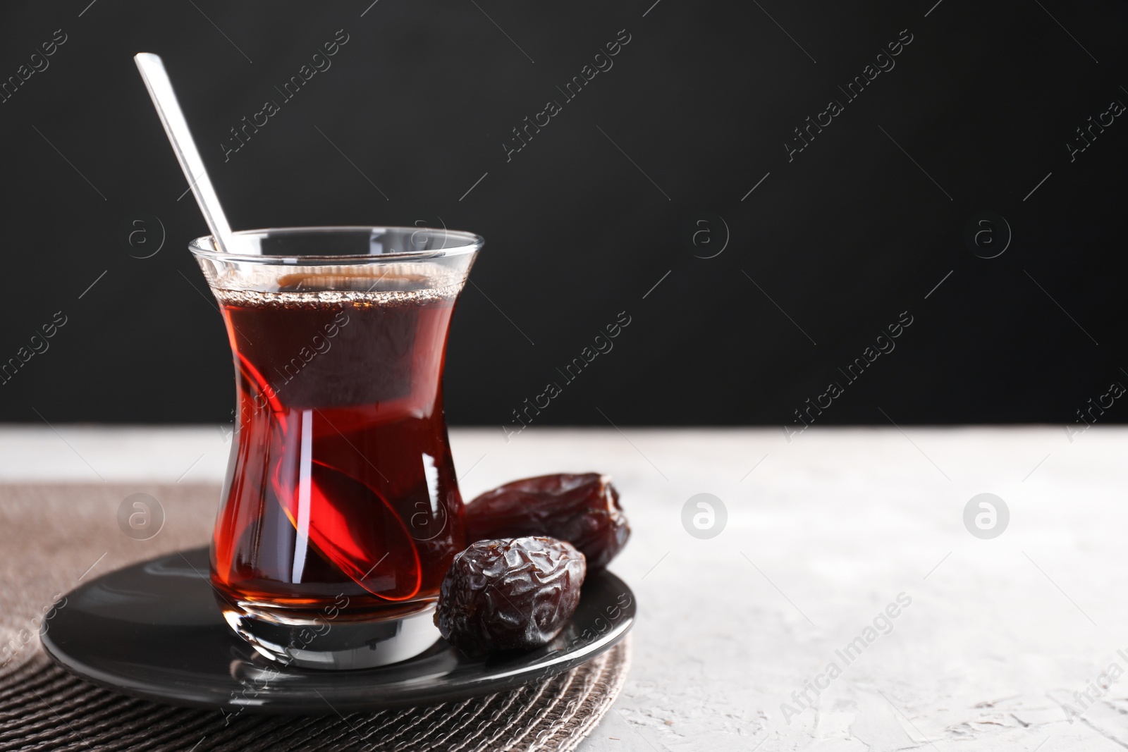 Traditional Turkish tea in glass cup and dates on light grey table, closeup. Space for text Photo of Traditional Turkish tea in glass cup and dates on light grey table, closeup. Space for text