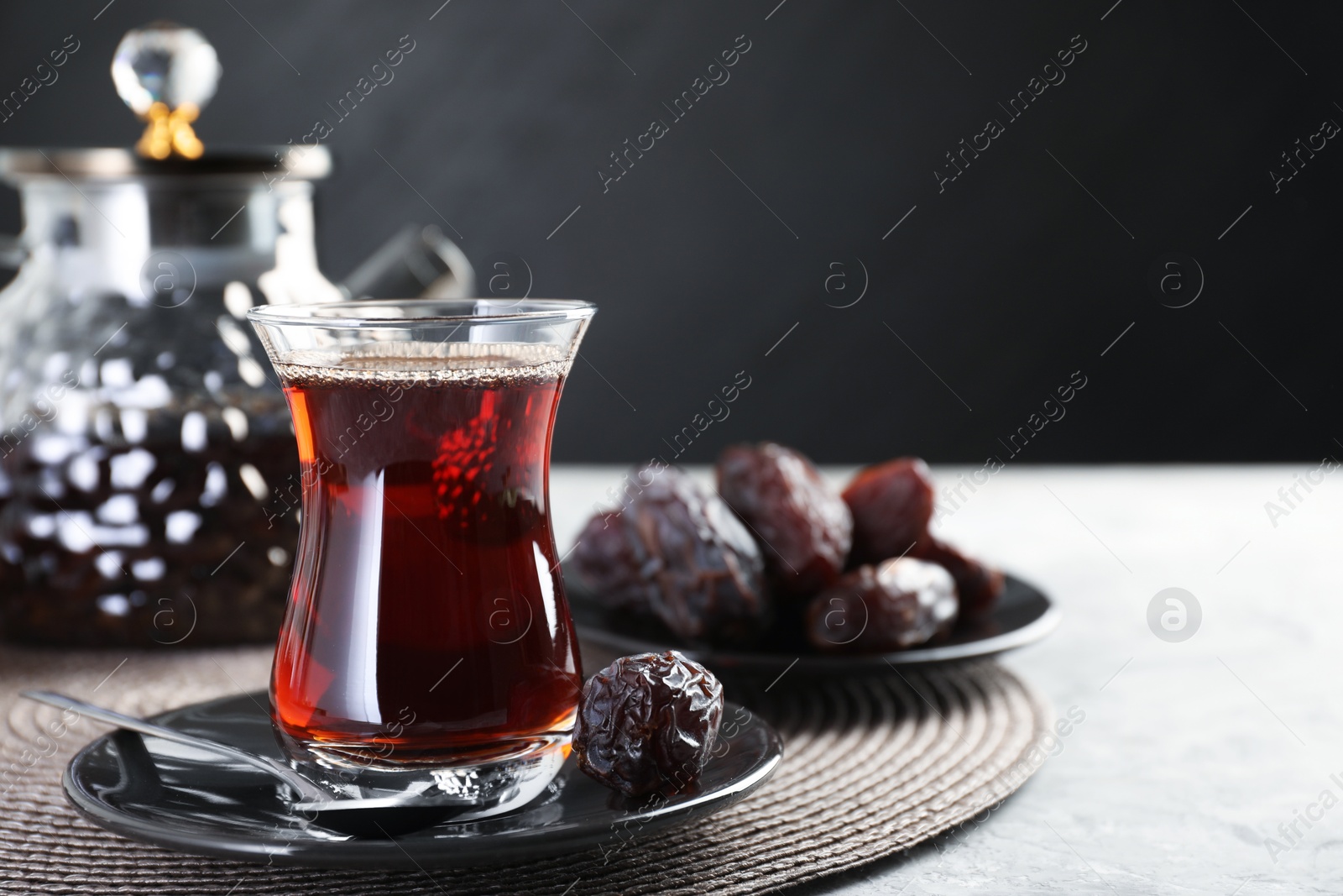 Traditional Turkish tea in glass cup, teapot and dates on light grey table, closeup. Space for text Photo of Traditional Turkish tea in glass cup, teapot and dates on light grey table, closeup. Space for text