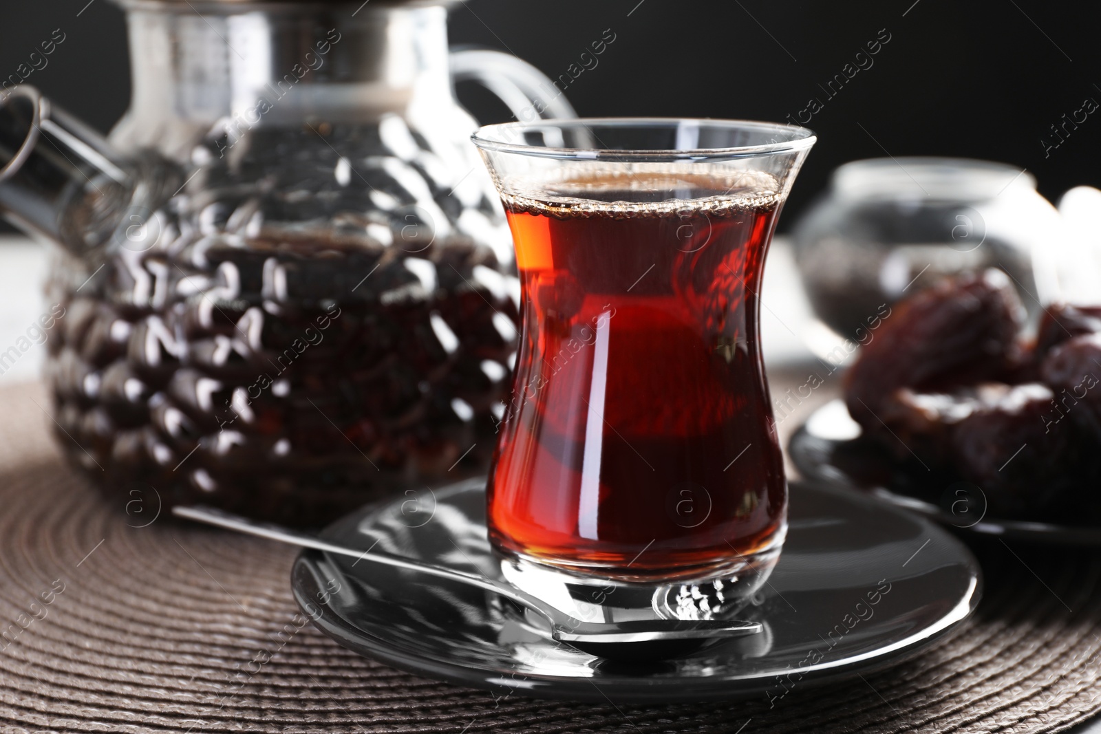Traditional Turkish tea in glass cup, teapot and dates on table, closeup Photo of Traditional Turkish tea in glass cup, teapot and dates on table, closeup