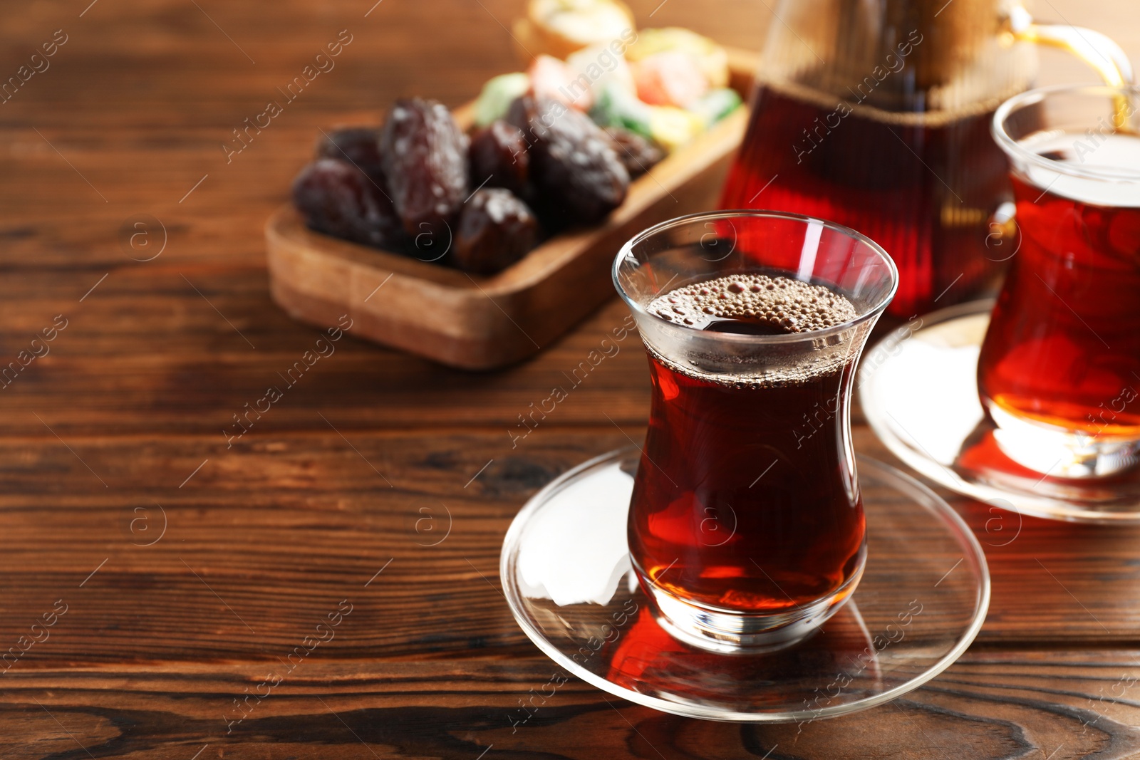 Traditional Turkish tea in glass cups, teapot and sweets on wooden table, closeup. Space for text Photo of Traditional Turkish tea in glass cups, teapot and sweets on wooden table, closeup. Space for text