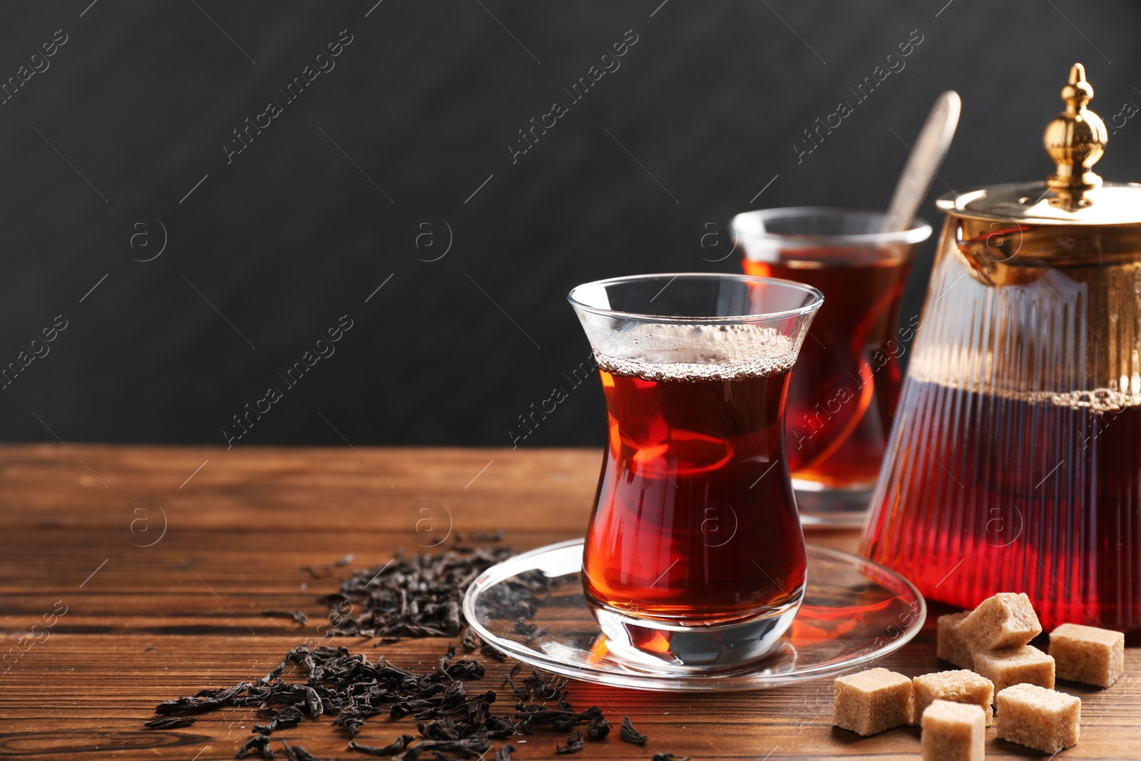 Traditional Turkish tea in glass cups, teapot, dry leaves and brown sugar on wooden table, closeup. Space for text Photo of Traditional Turkish tea in glass cups, teapot, dry leaves and brown sugar on wooden table, closeup. Space for text