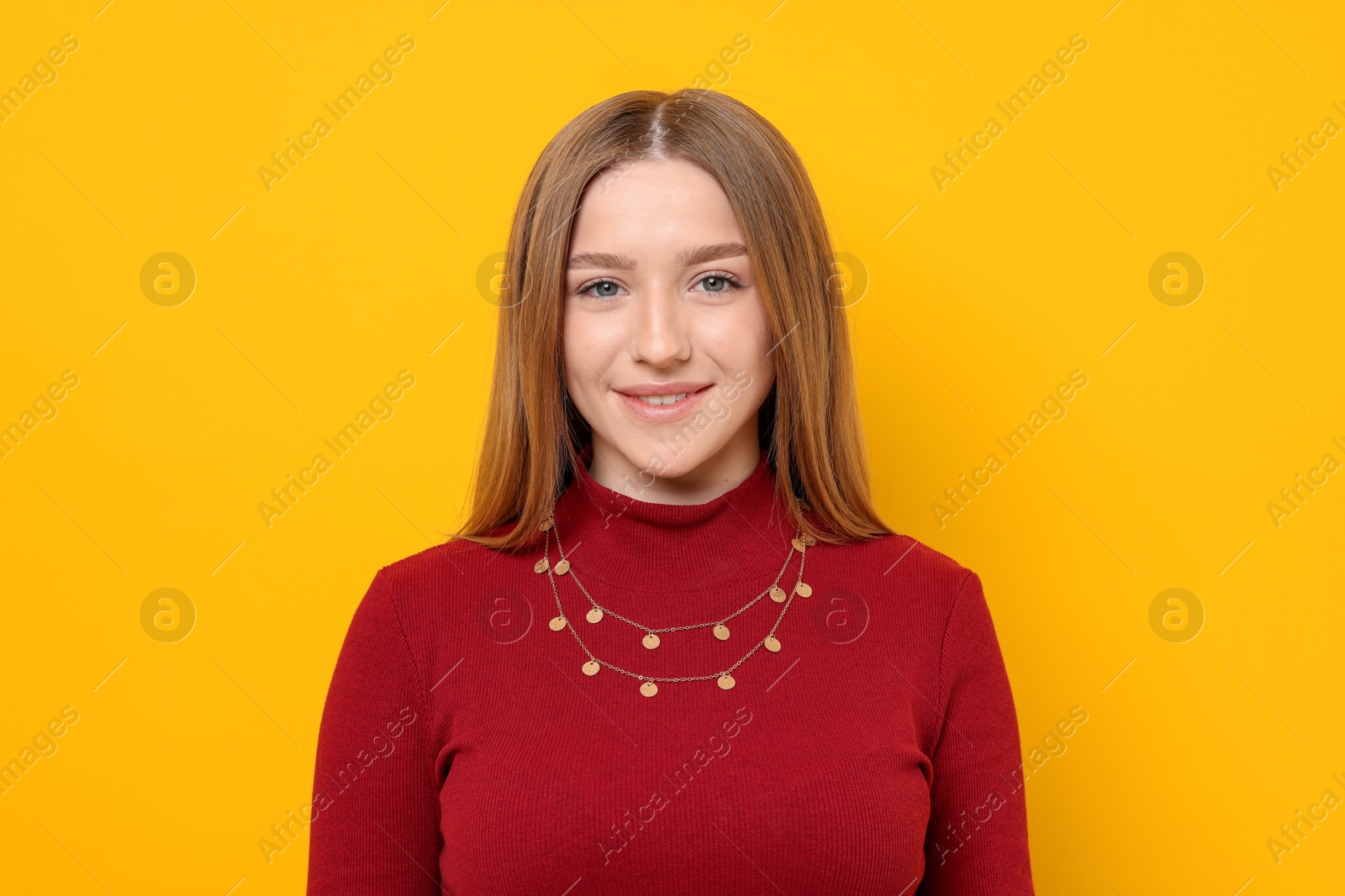 Portrait of smiling teenage girl on yellow background Photo of Portrait of smiling teenage girl on yellow background