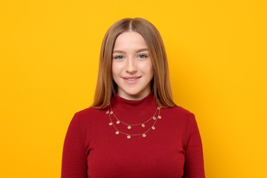 Photo of Portrait of smiling teenage girl on yellow background
