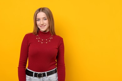 Photo of Portrait of smiling teenage girl on yellow background. Space for text