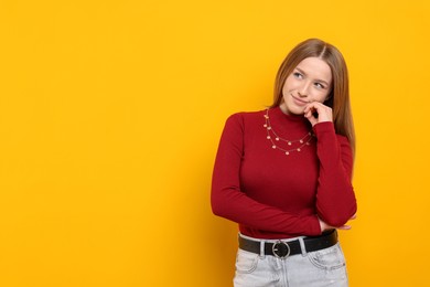 Photo of Portrait of thoughtful teenage girl on yellow background. Space for text