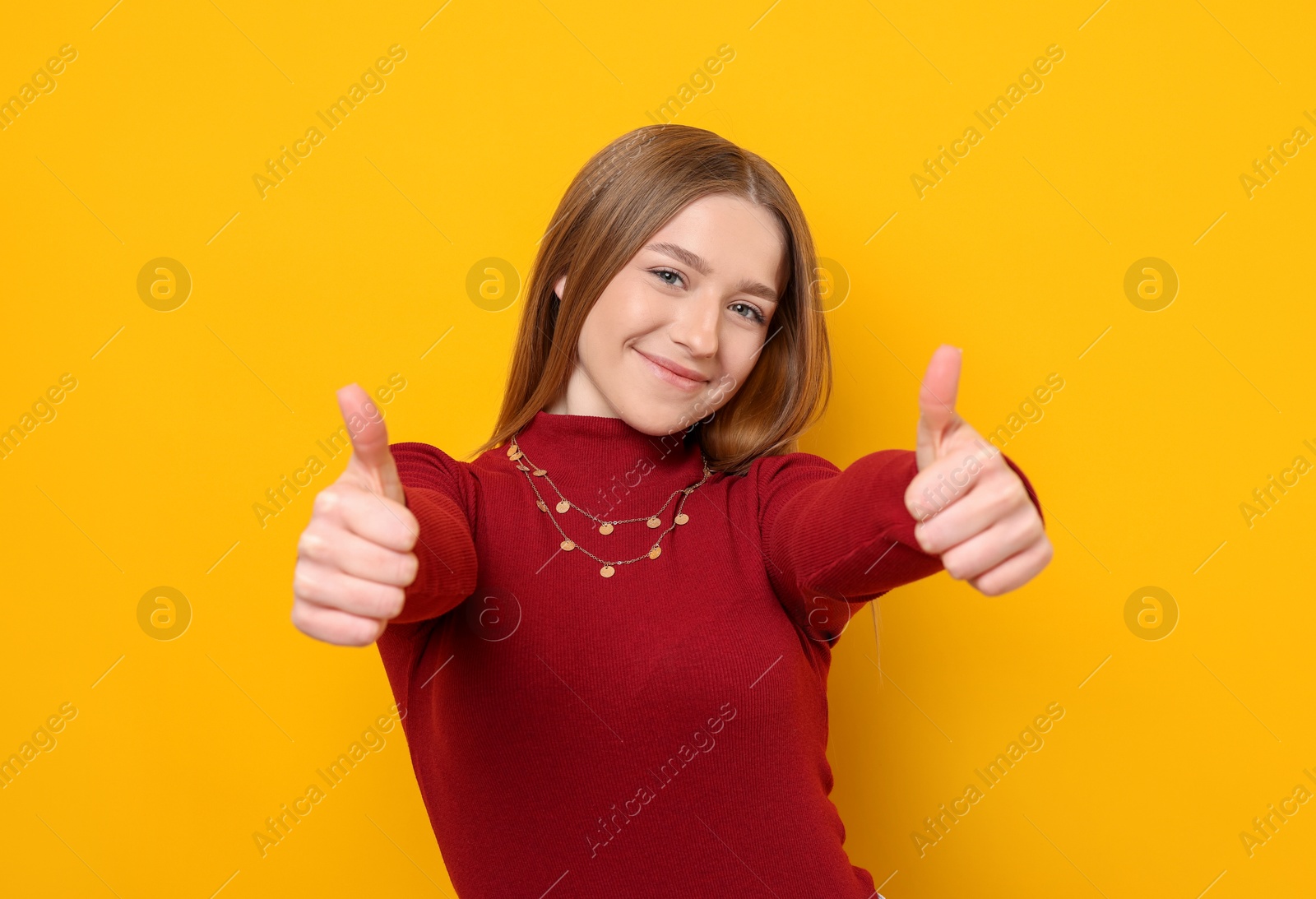 Photo of Portrait of teenage girl showing thumbs up on yellow background