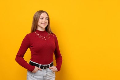 Photo of Portrait of smiling teenage girl on yellow background. Space for text