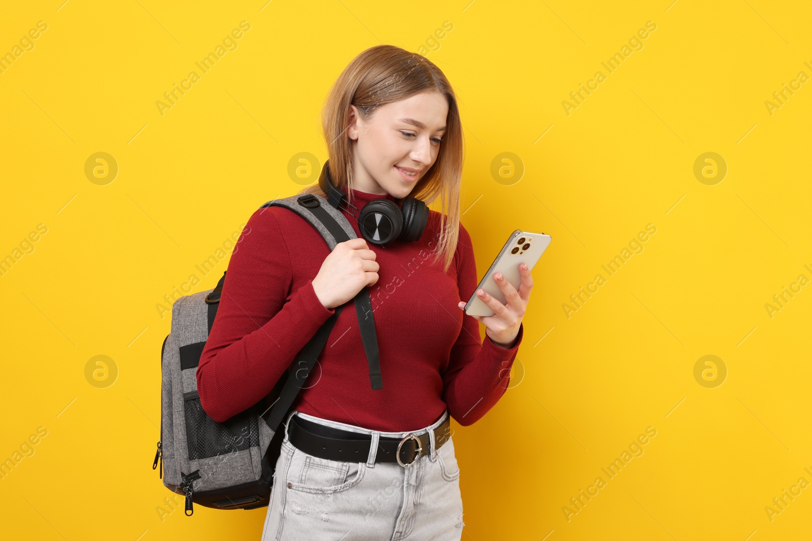 Smiling teenage girl with smartphone on yellow background Photo of Smiling teenage girl with smartphone on yellow background