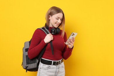 Photo of Smiling teenage girl with smartphone on yellow background