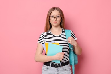 Photo of Portrait of teenage girl with books and backpack on pink background