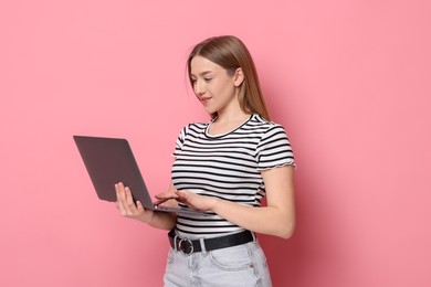 Photo of Smiling teenage girl with laptop on pink background