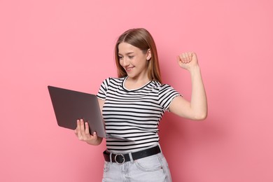 Photo of Smiling teenage girl with laptop on pink background