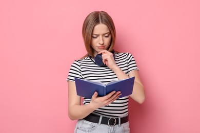 Photo of Thoughtful teenage girl with book on pink background