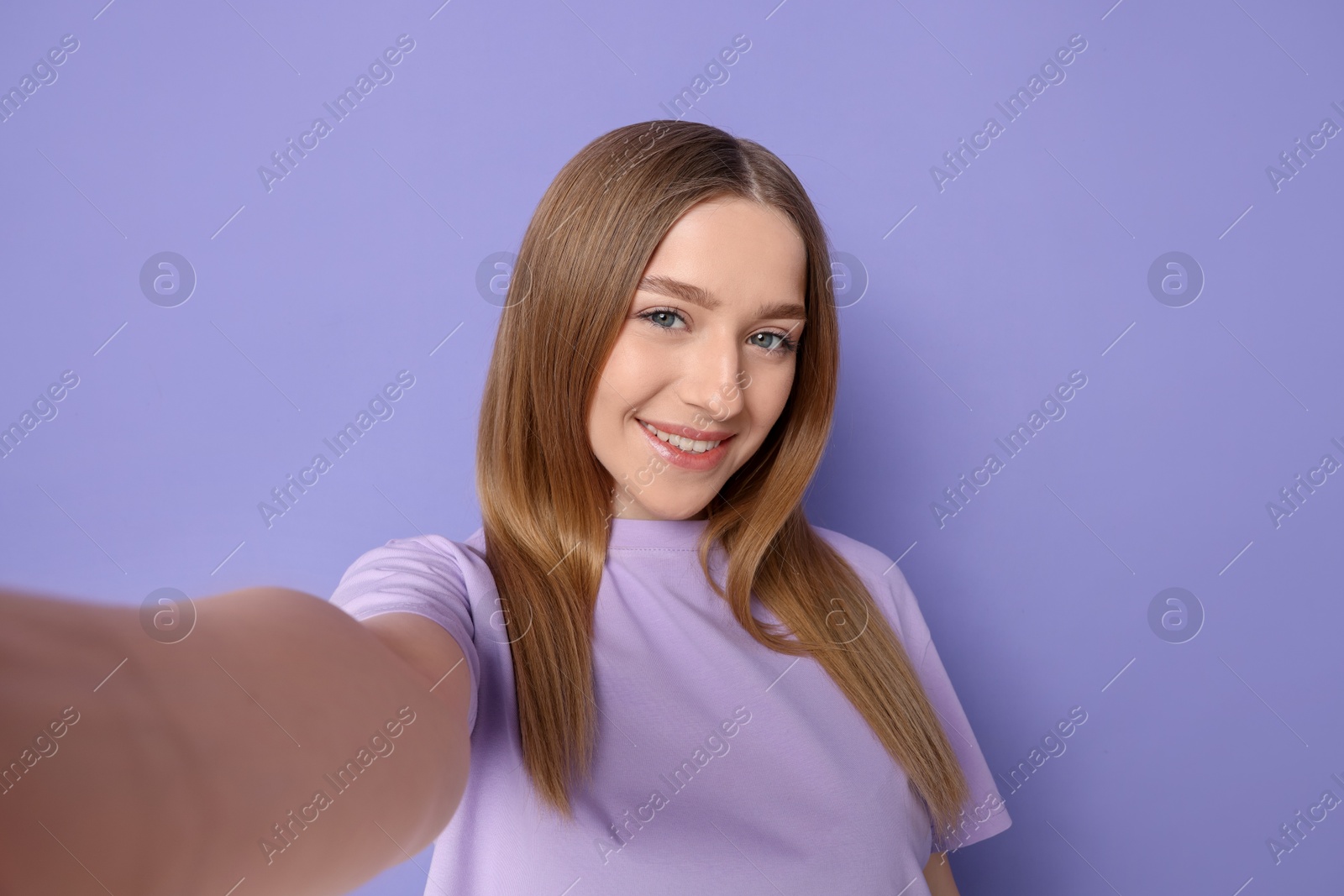 Photo of Smiling teenage girl taking selfie on violet background