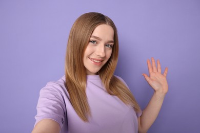 Photo of Smiling teenage girl taking selfie on violet background