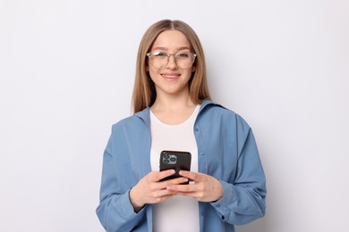 Photo of Portrait of smiling teenage girl with smartphone on white background