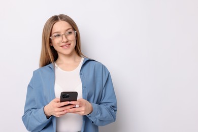 Photo of Portrait of smiling teenage girl with smartphone on white background. Space for text