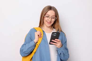 Photo of Smiling teenage girl with smartphone and backpack on white background