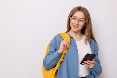 Photo of Smiling teenage girl with smartphone and backpack on white background. Space for text