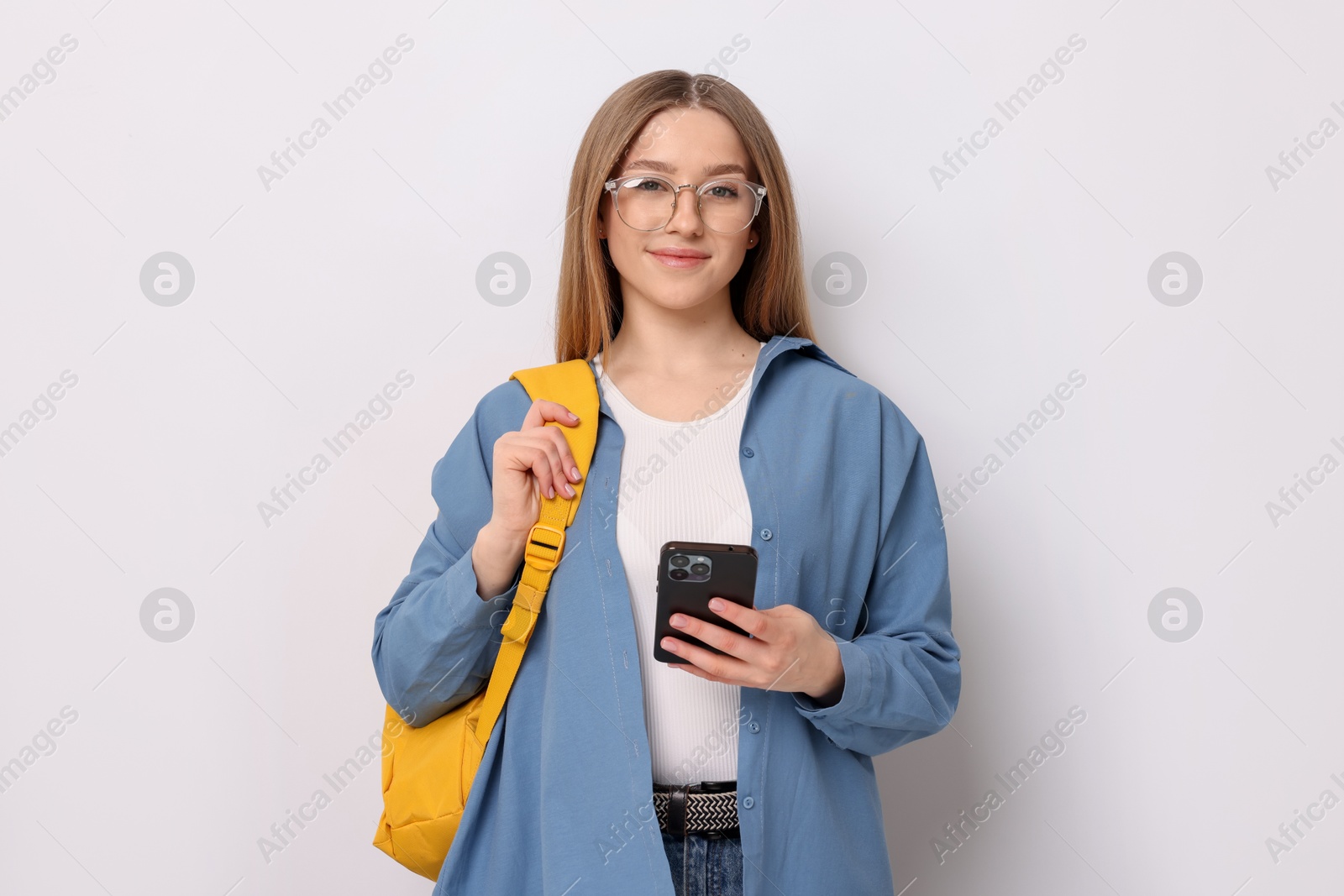 Photo of Beautiful teenage girl with smartphone and backpack on white background