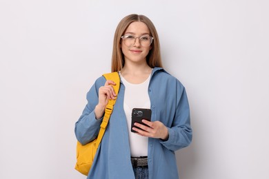 Photo of Beautiful teenage girl with smartphone and backpack on white background