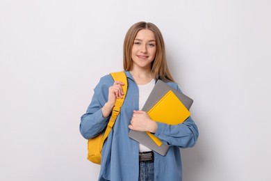 Photo of Smiling teenage girl with books and backpack on white background