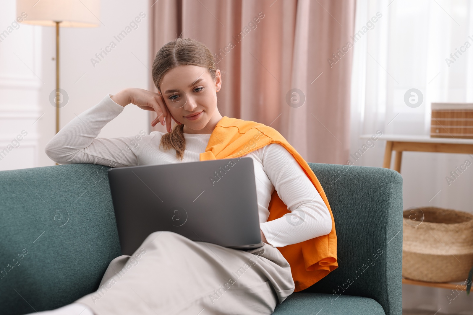 Photo of Teenage girl with laptop on sofa at home