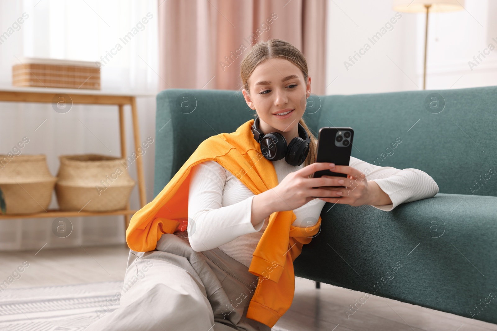 Smiling teenage girl with smartphone at home Photo of Smiling teenage girl with smartphone at home