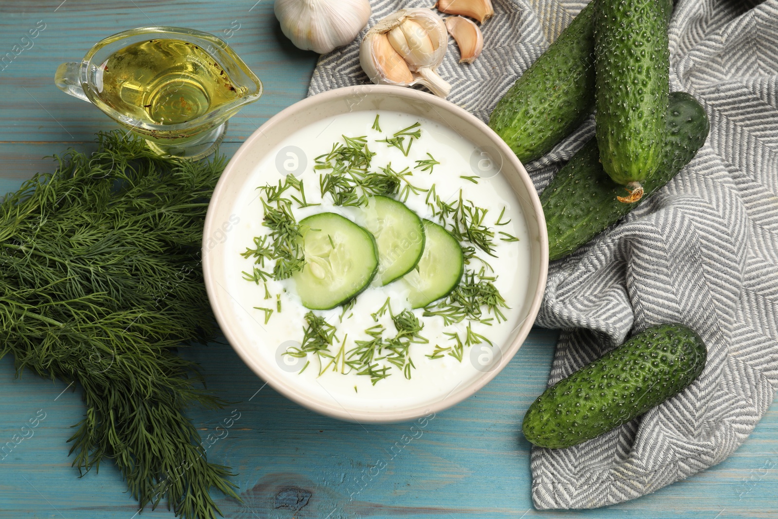 Tasty cucumber soup in bowl and ingredients on light blue wooden table, flat lay Photo of Tasty cucumber soup in bowl and ingredients on light blue wooden table, flat lay