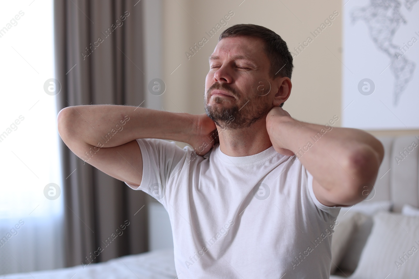 Man suffering from neck pain on bed at home Photo of Man suffering from neck pain on bed at home