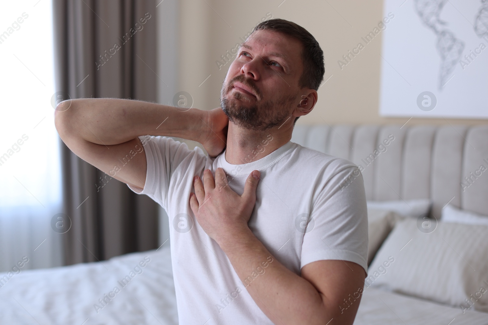 Man suffering from neck pain on bed at home Photo of Man suffering from neck pain on bed at home