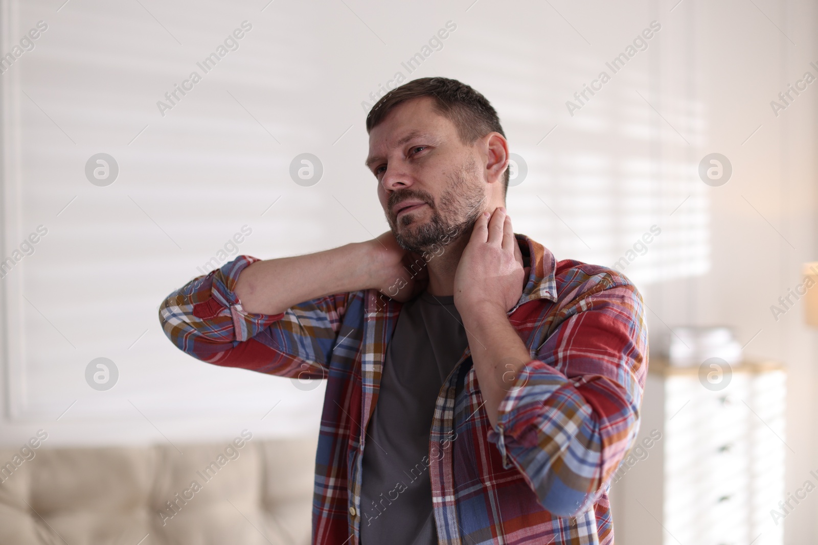 Man suffering from neck pain at home Photo of Man suffering from neck pain at home