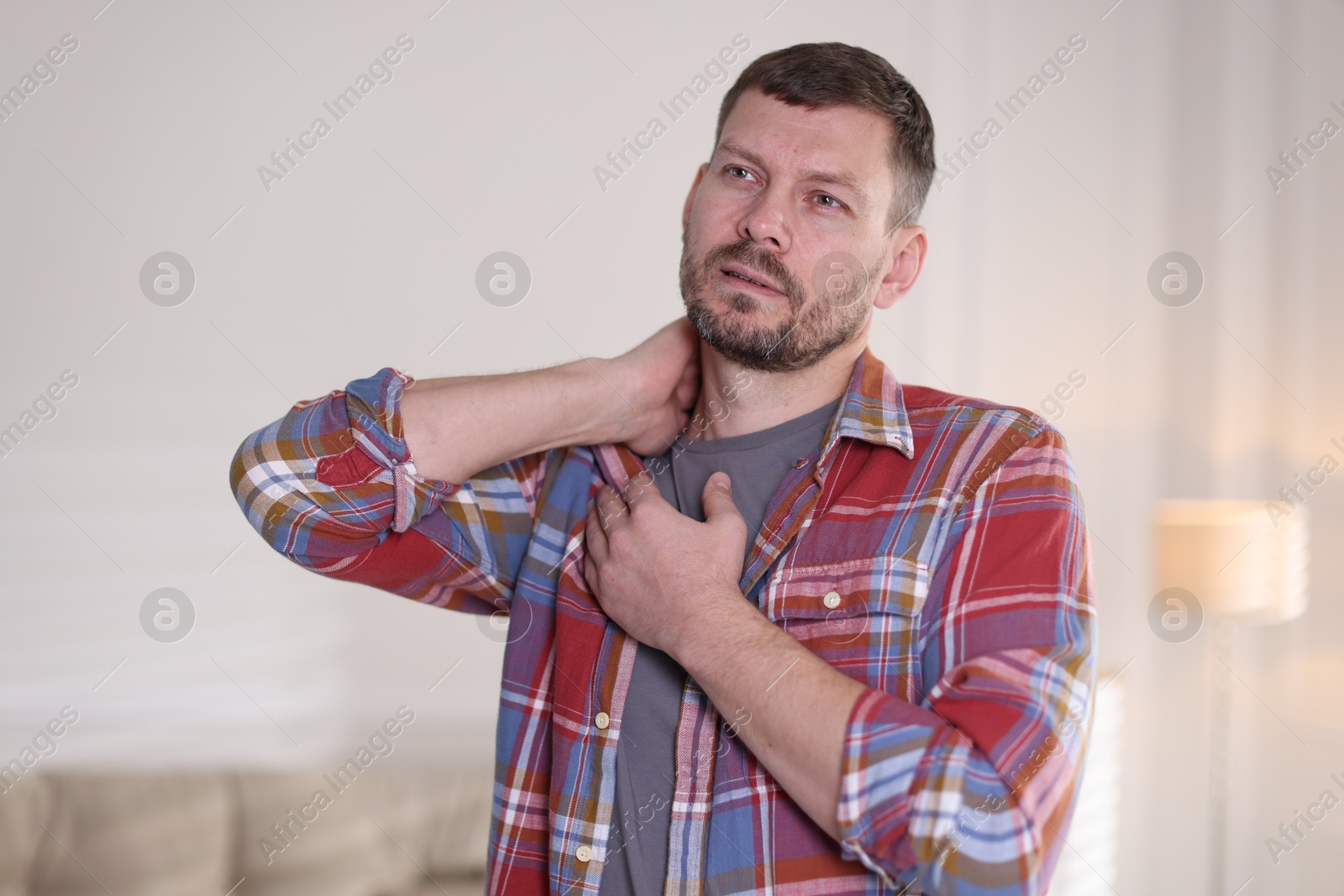 Man suffering from neck pain at home Photo of Man suffering from neck pain at home