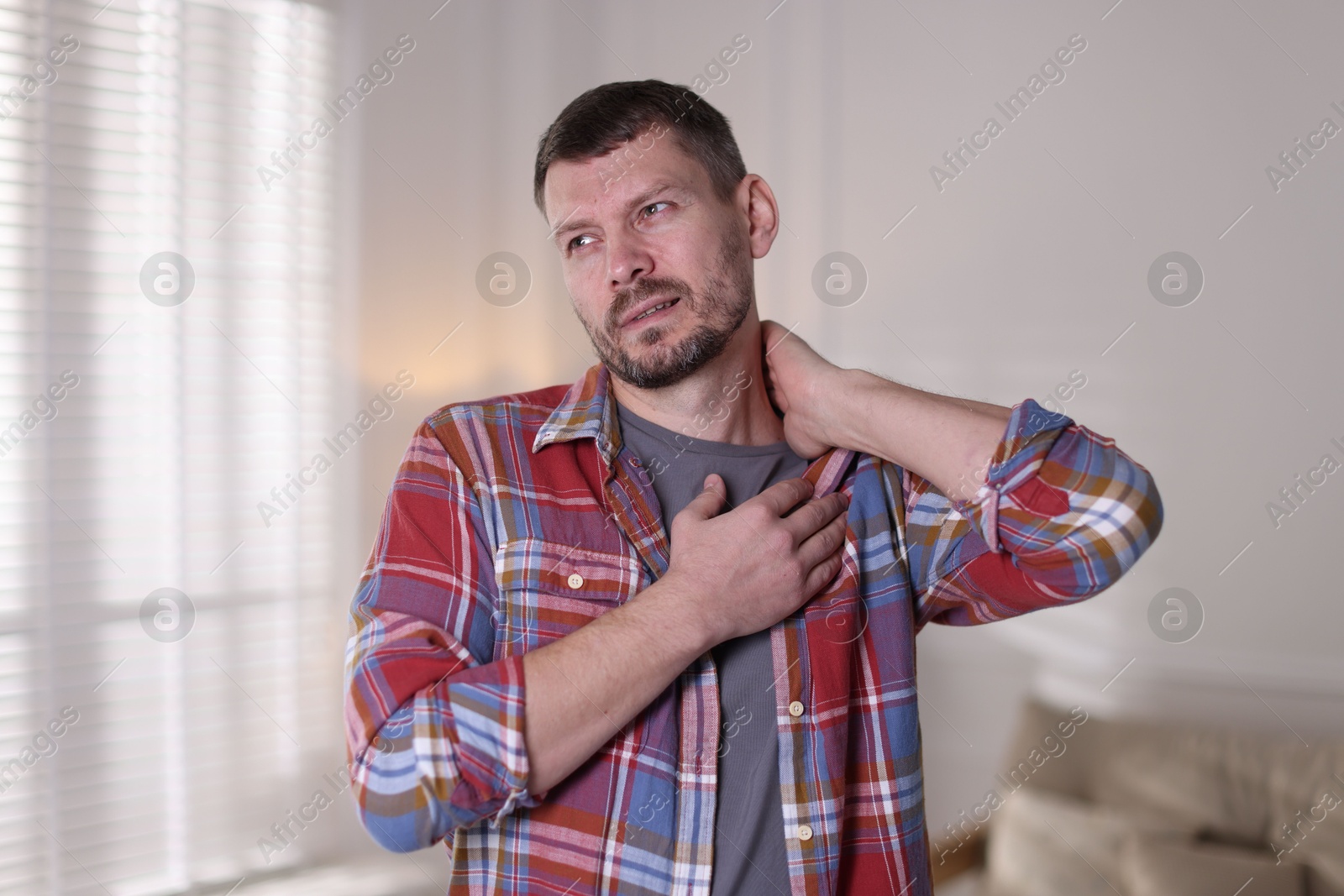Man suffering from neck pain at home Photo of Man suffering from neck pain at home