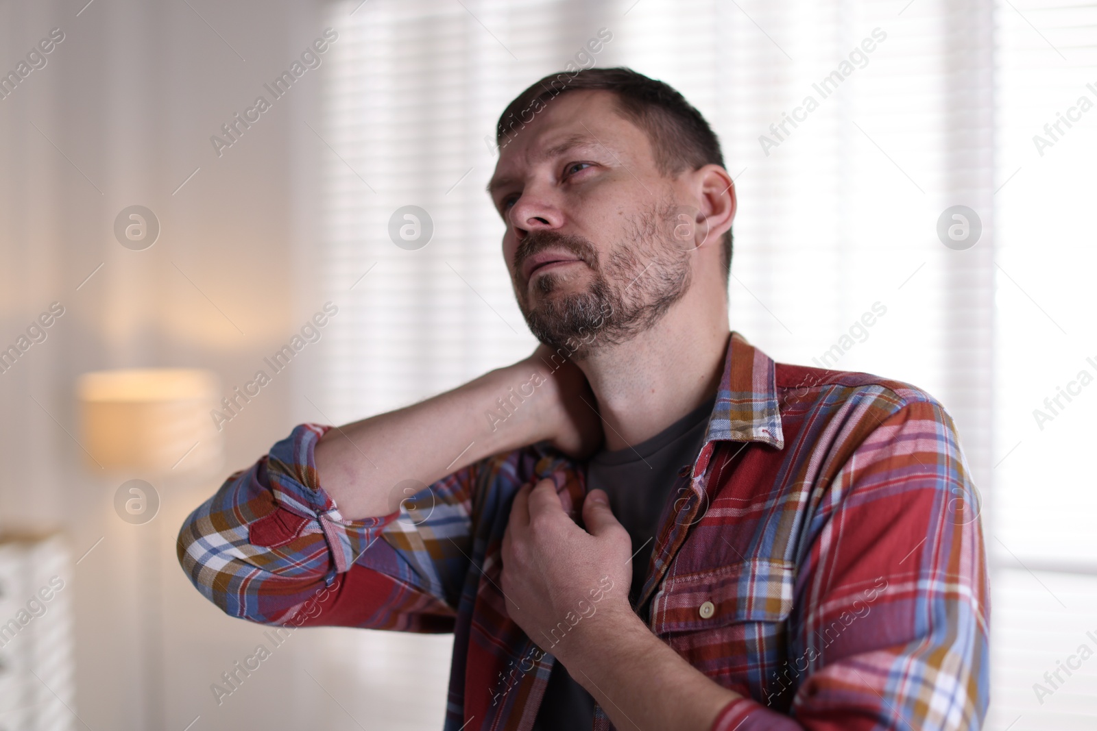 Man suffering from neck pain at home Photo of Man suffering from neck pain at home