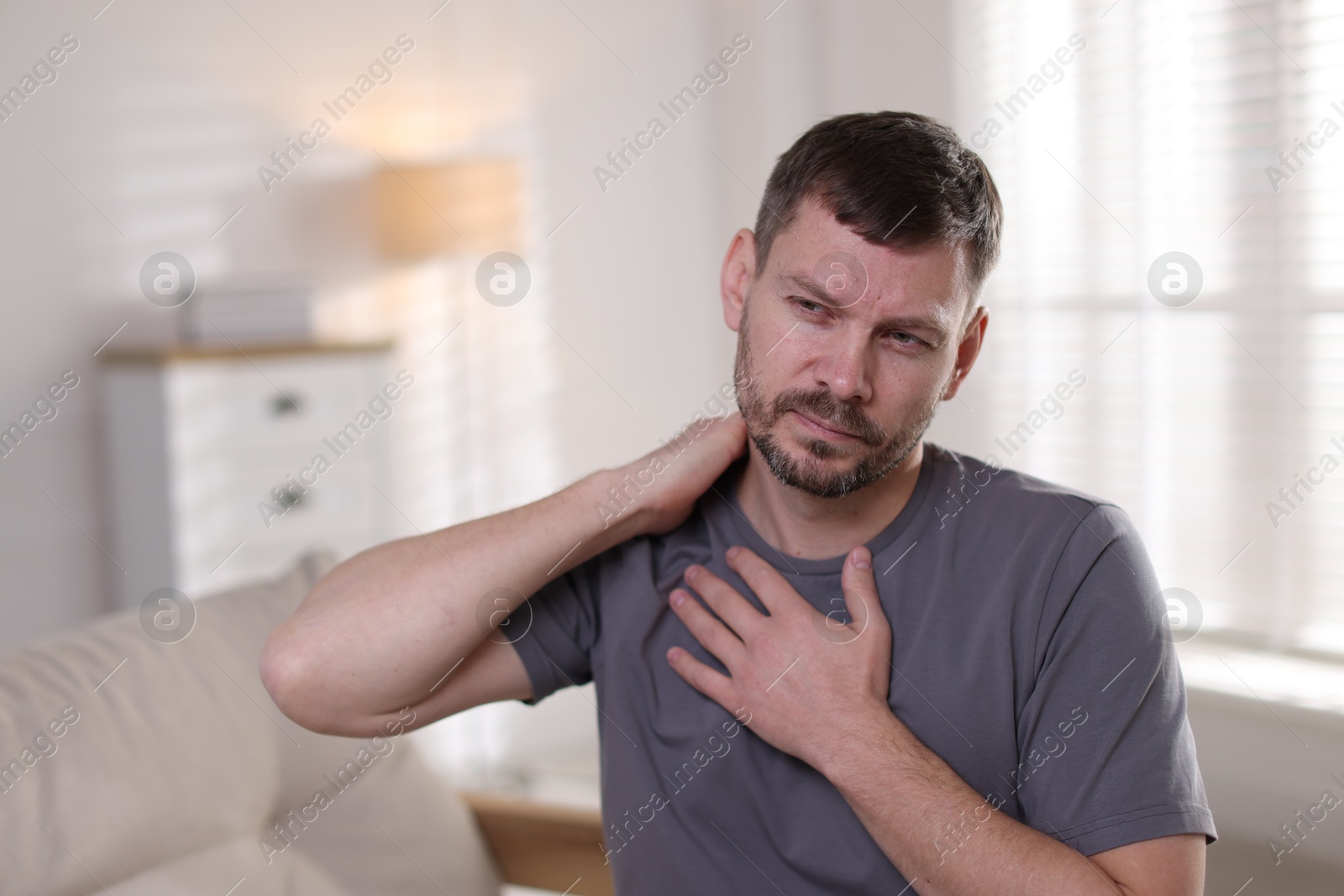 Man suffering from neck pain at home Photo of Man suffering from neck pain at home