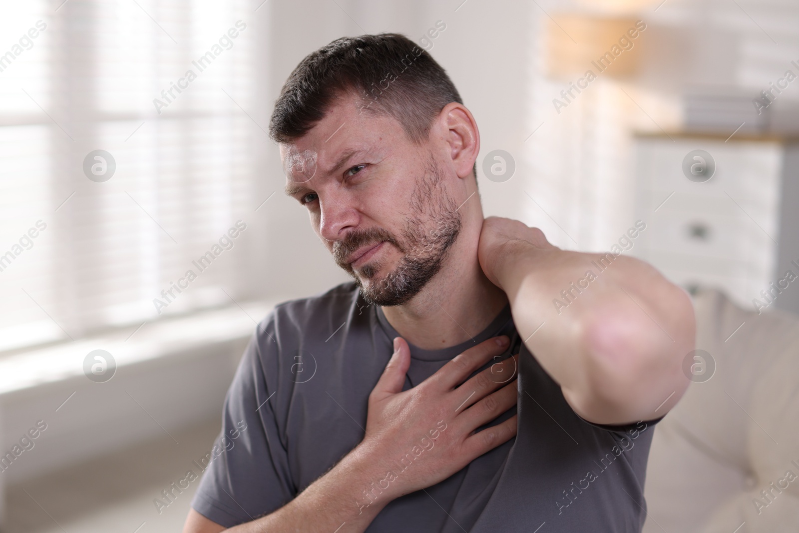 Man suffering from neck pain at home Photo of Man suffering from neck pain at home