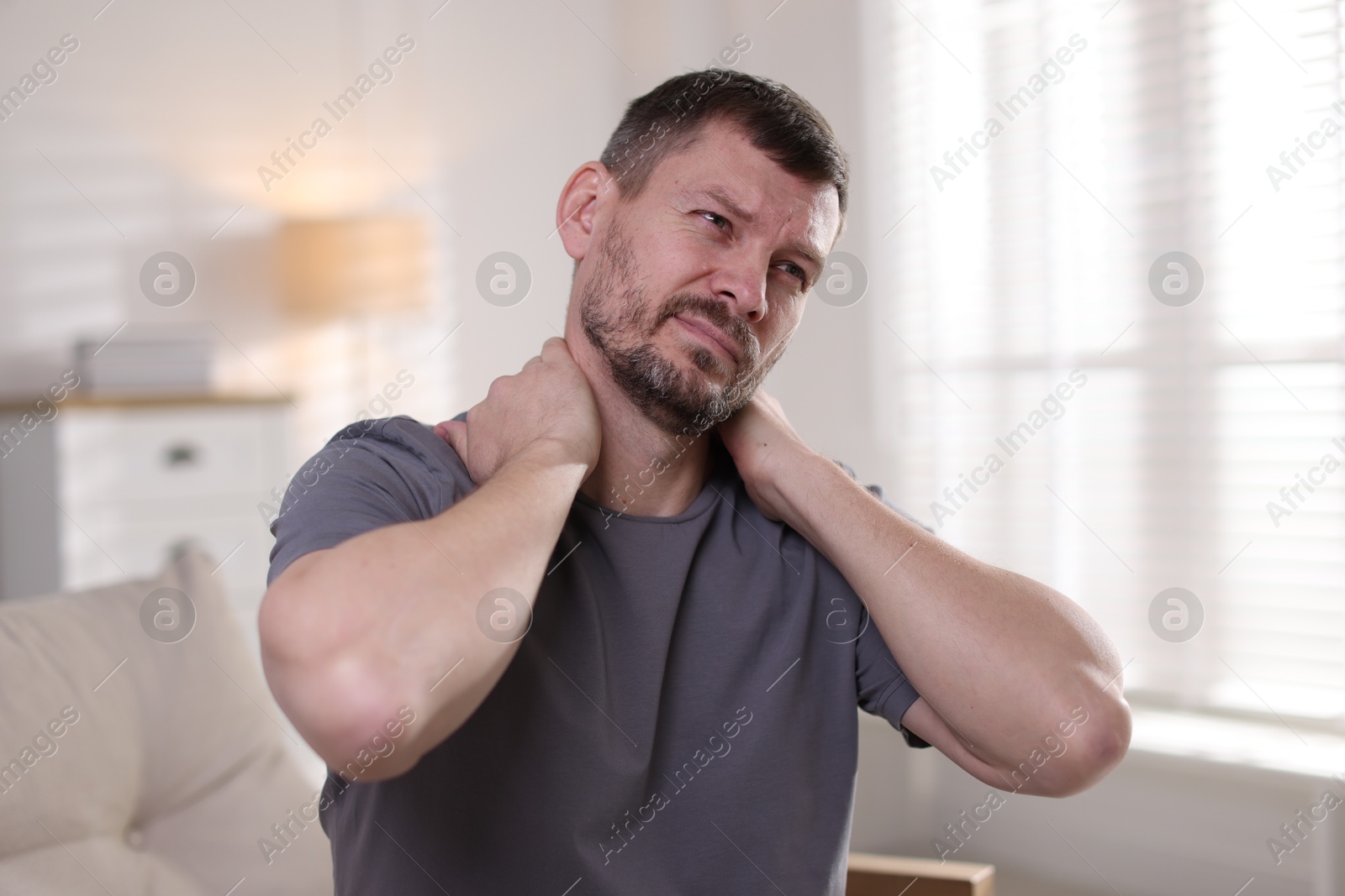 Man suffering from neck pain at home Photo of Man suffering from neck pain at home
