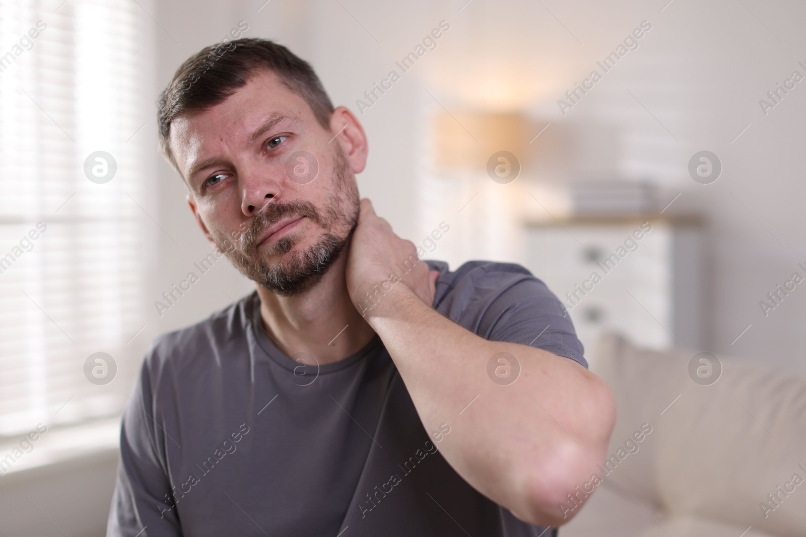 Man suffering from neck pain at home Photo of Man suffering from neck pain at home