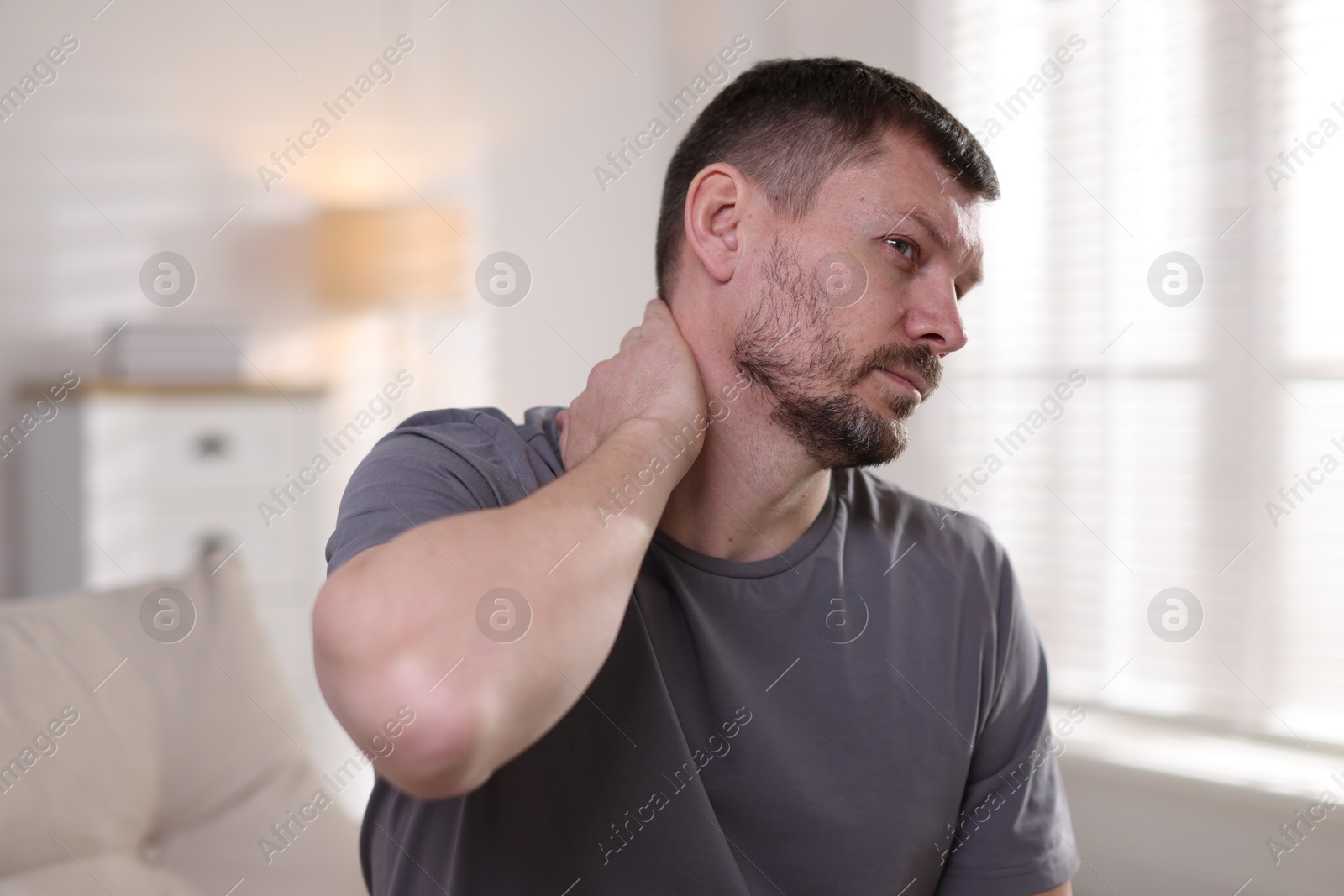 Man suffering from neck pain at home Photo of Man suffering from neck pain at home