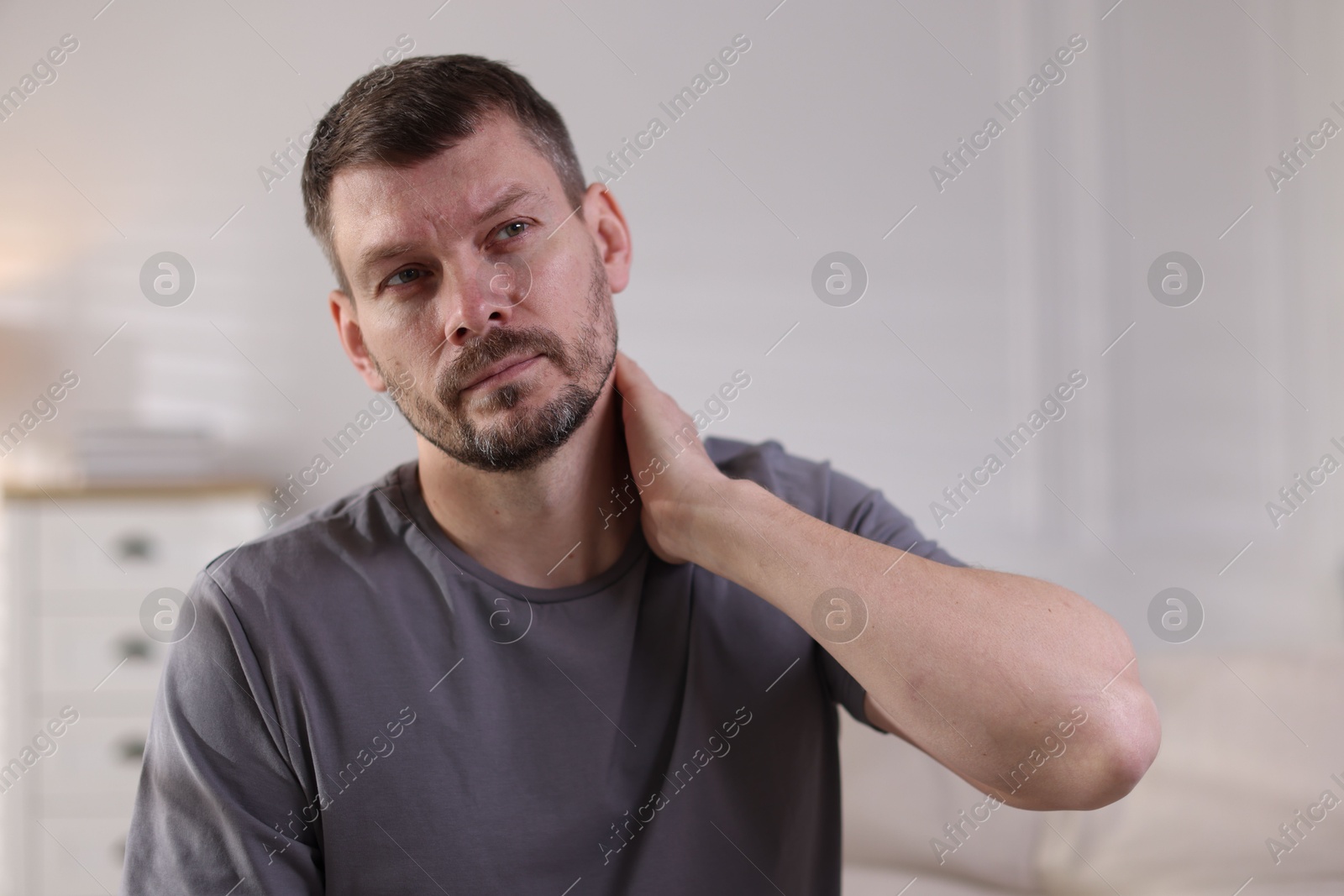 Man suffering from neck pain at home Photo of Man suffering from neck pain at home