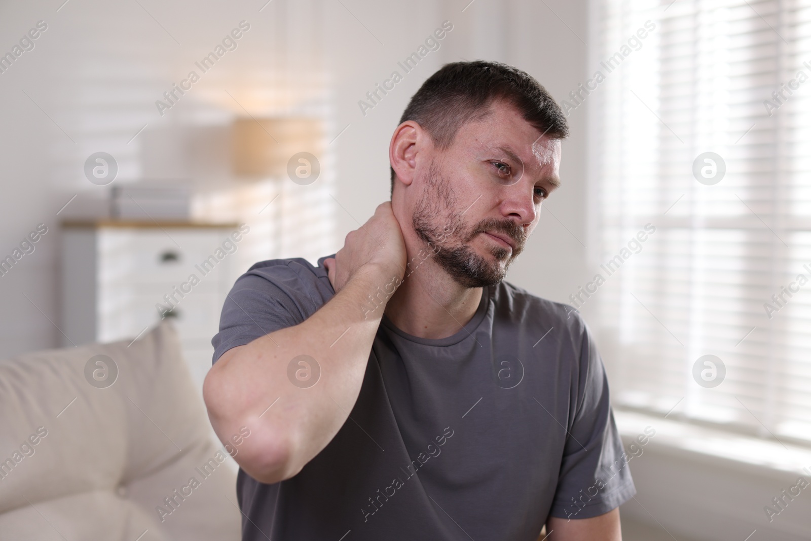 Man suffering from neck pain at home Photo of Man suffering from neck pain at home