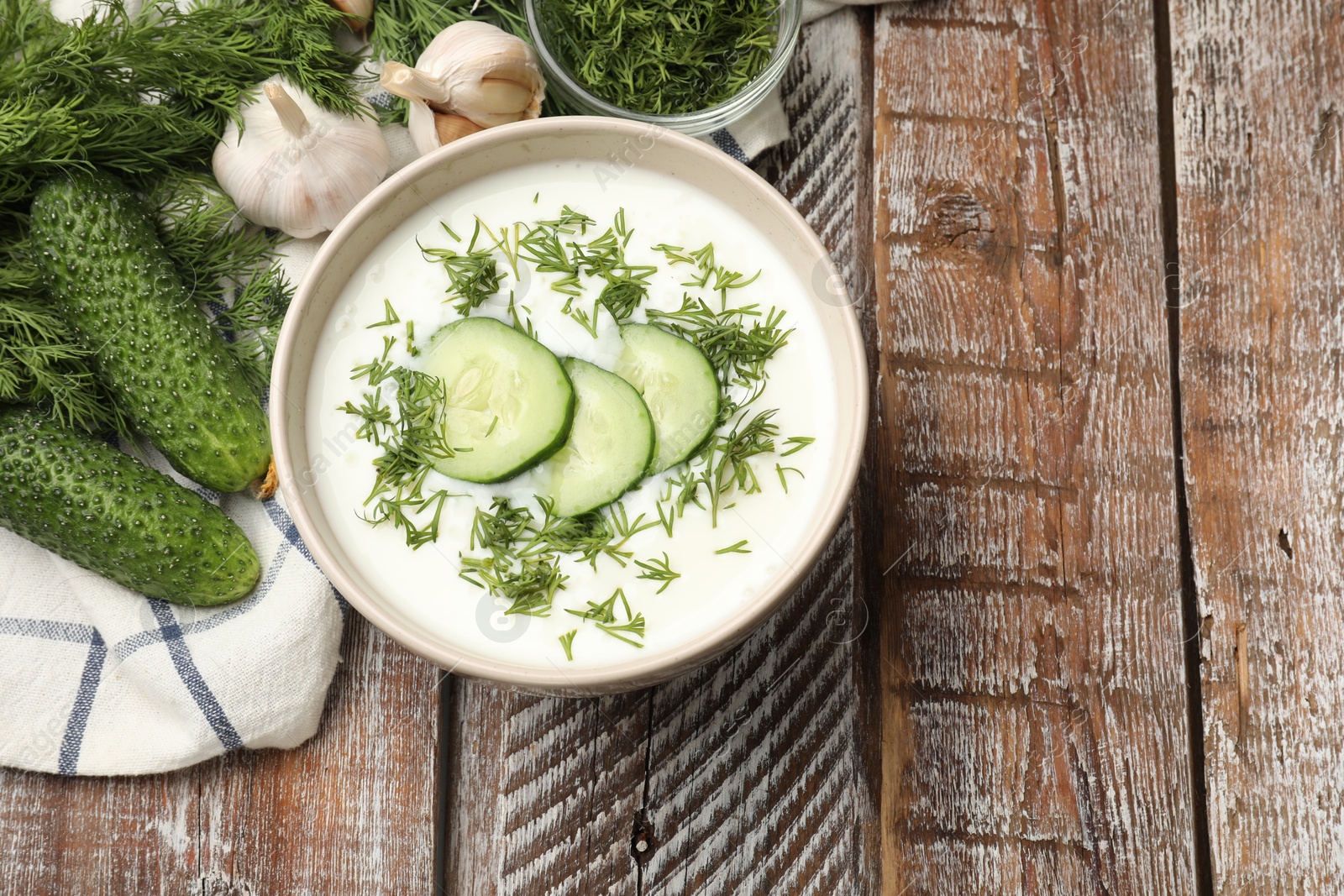 Tasty cucumber soup in bowl and ingredients on wooden table, flat lay. Space for text Photo of Tasty cucumber soup in bowl and ingredients on wooden table, flat lay. Space for text