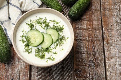 Photo of Tasty cucumber soup in bowl on wooden table, flat lay. Space for text