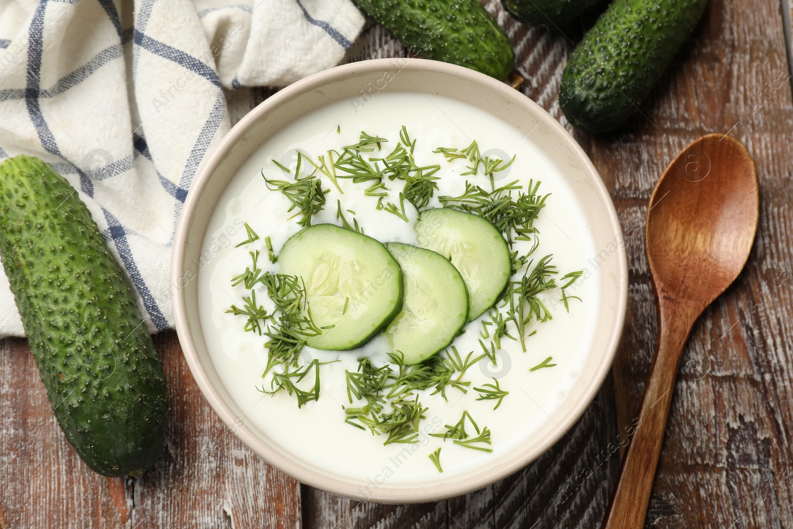 Tasty cucumber soup in bowl on wooden table, flat lay Photo of Tasty cucumber soup in bowl on wooden table, flat lay