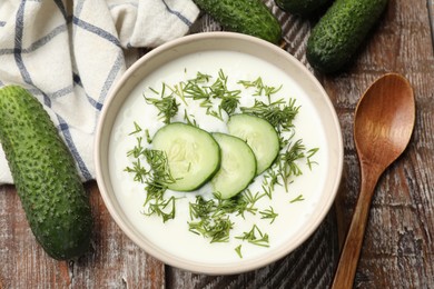 Photo of Tasty cucumber soup in bowl on wooden table, flat lay