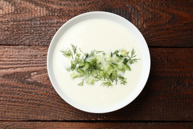 Photo of Tasty cucumber soup in bowl on wooden table, top view
